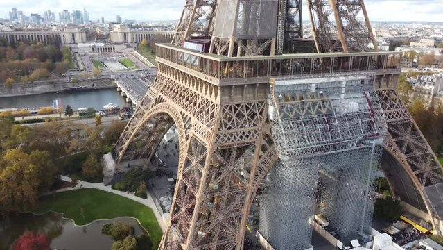 Drone footage of the Eiffel Tower from the side along with scaffolding.
