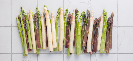 Green, purple and white asparagus on kitchen tiles 
