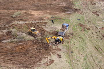 Bulldozer, excavator and dump truck level the ground