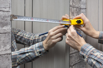 a woman measures a mirror fixed on the wall with a tape measure