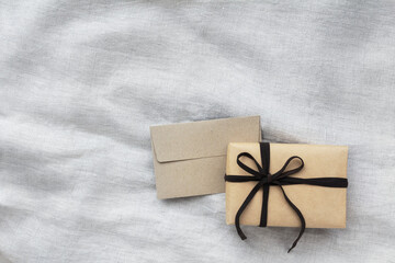 メッセージカードサイズの封筒とプレゼントと明るいグレーのテクスチャのある布の背景	