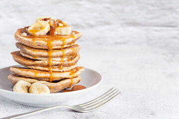 Wholegrain pancakes with banana and caramel sauce. Delicious breakfast.