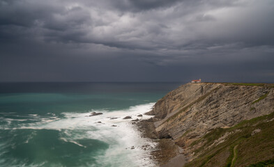 view of the lighthouse on the cliffs at Cabo Vidio under an overcast and stormy sky