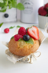 Muffin with fresh berries on the table with strawberries, blueberries, raspberries and mint close up