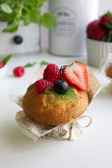 Muffin with fresh berries on the table with strawberries, blueberries, raspberries and mint close up