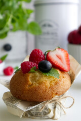 Muffin with fresh berries on the table with strawberries, blueberries, raspberries and mint close up