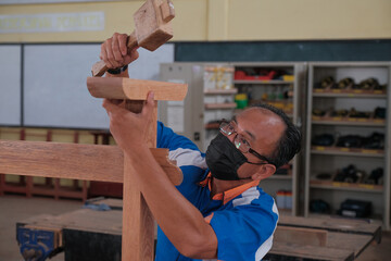 Senior male woodworker making console table  in workshop. Joinery work on the production  of wooden...