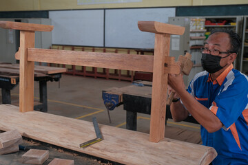 Senior male woodworker making console table  in workshop. Joinery work on the production  of wooden furniture. Small Business Concept