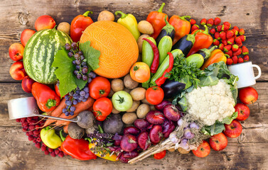 A harvest of fruits, vegetables and berries, collected in a large pile on a wooden countertop.