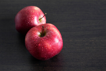 Red apples in water drops on a wooden background