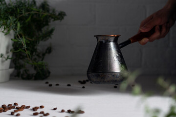 A woman's hand puts a coffee pot on a table with coffee beans. Fresh coffee.