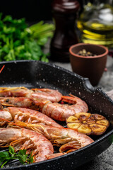 Grilled tiger shrimps with spice, lemon and garlic in a frying pan on a dark background. Prawns fried on a dark background, Seafood appetizer, Culinary, cooking concept, top view