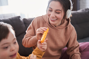 Happy woman playing at the building kit with her son with down syndrome