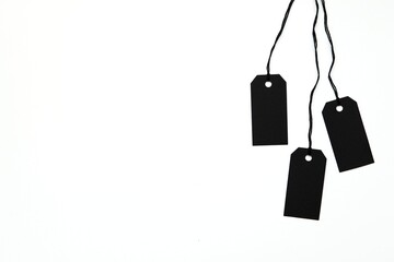 Three black price tags hanging on strings, empty product labels mockup, Black Friday, sale, discounting concept, white background, space for text.