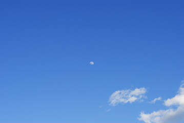 Full moon in the blue sky landscape with a wispy white cloud floating by