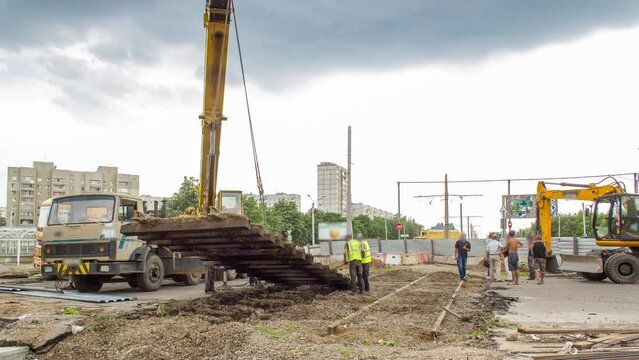Demolition of old tram rails by crane at road construction site timelapse.