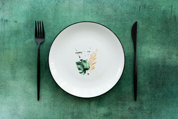 white ceramic plate with a pattern and cutlery on a green table