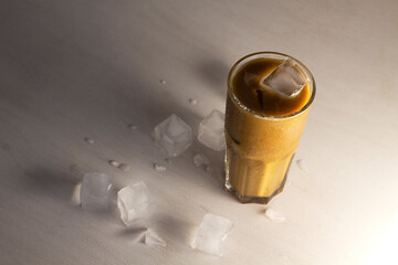 Delicious invigorating coffee with milk and ice. Drink with ice on the table