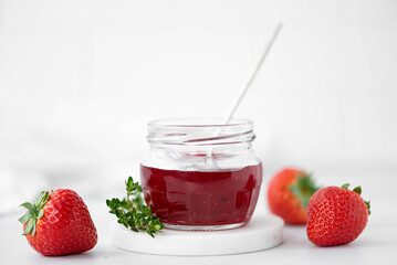 homemade strawberry jam and fresh strawberries on a white table