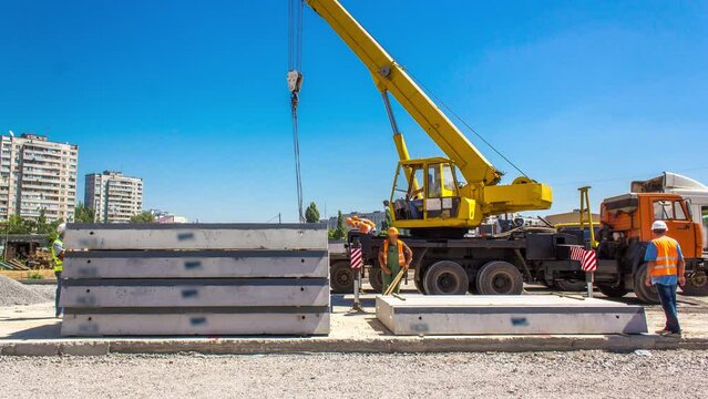 Unloading concrete plates by crane at road construction site timelapse.