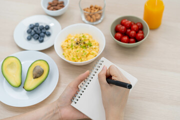 Diet, Dieting hand of asian young woman, girl write diet plan nutrition on table is different food ingredients in the green. Nutritionist of healthy, nutrition of weight loss, health care people.