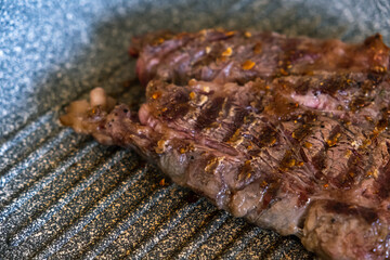 Juicy beef meat steak cooking on griddle pan at professional kitchen. Prime steak frying at grill. Delicious, modern cuisine.