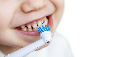 close up of child's, little boy's mouth brushing teeth with electric toothbrush. wide banner, white background. dental care, dentist for kids concept. smiling boy, diastema. space for text.