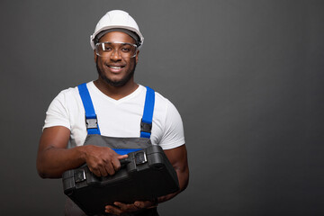Satisfied foreman carpenter in protective glasses and a helmet holds in front of him a large set of...