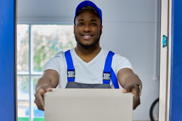 Close up of a handsome young man happily unpacking boxes in a new house on the day of the move. An...