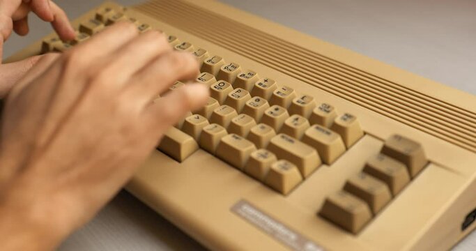 Man hand typing on old 8 bit computer from the 80's