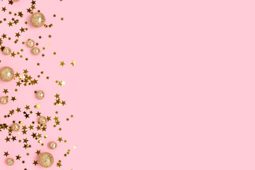 Various gold colored glittering confetti on a pink pastel background with copy space.