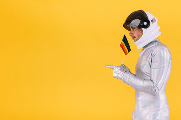 Gay man dressed as an astronaut with a helmet and silver suit, with a flag of the lgtbi collective,...