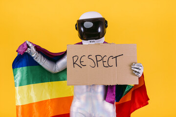 Gay man dressed as an astronaut with a helmet and silver suit, holding a flag of the trans...