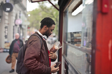 young man buys some bread in a kiosk