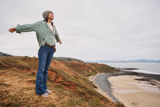 Asian girl feeling freedom in the seaside in Autumn time.