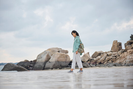 Beautiful Asian girl walking on the beach in Autumn during her trip