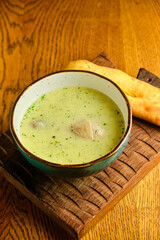 Peas soup in the yellow bowl on the wooden background.