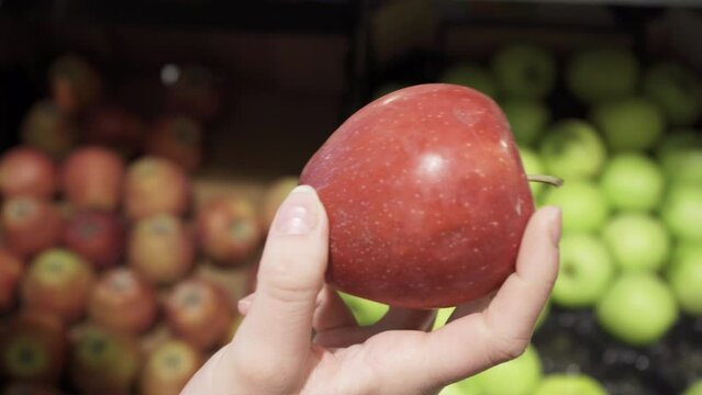  Woman picks up apple and inspects it.