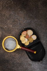 Magnifying glass and leather change purse with eurocents on a background of stone with copy space