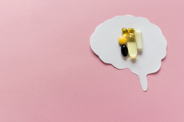 Medical concept with paper brain cut out and vitamins pills, capsules on pink background