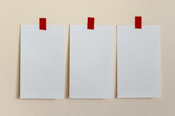 Mockup template with three white blank cards attached with red tapes to yellow wall