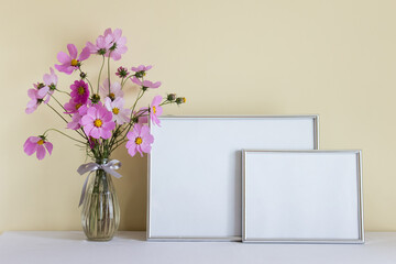 Large silver horizontal A4 mockup blank frame with pink summer flowers in glass vase on yellow wall background