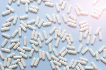 Many white pills capsules on blue background