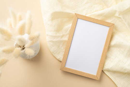 Top view photo of wooden photo frame linen and vase with white lagurus flowers on isolated beige background with blank space