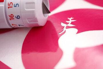 closeup on peace dove symbol of a pink vinyl sticker on white carrier paper. closely lying...