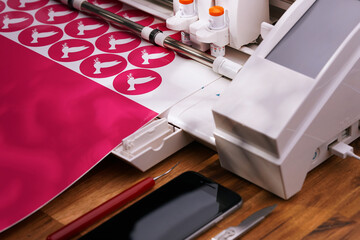 plotting machine cuts pink peace dove stickers from adhesive foil in vivid light. view on cosy...