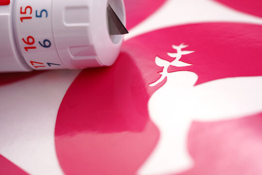 closeup on peace dove symbol of a pink vinyl sticker on white carrier paper. closely lying adjustable plotting blade. selective focus. peace and anti-war movement concept