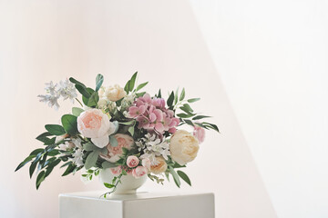 A composition of different flowers in a white vase on a square podium. The concept of a flower shop. A beautiful freshly cut bouquet. Flower delivery. High quality photo © daryakomarova