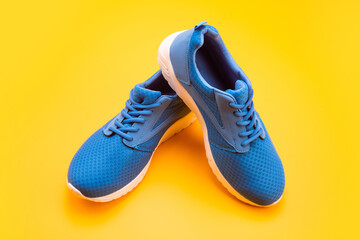 pair of comfortable sport shoes. sporty blue sneakers. shoes on yellow background.