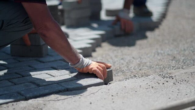 Worker lining paving slabs path, slow motion